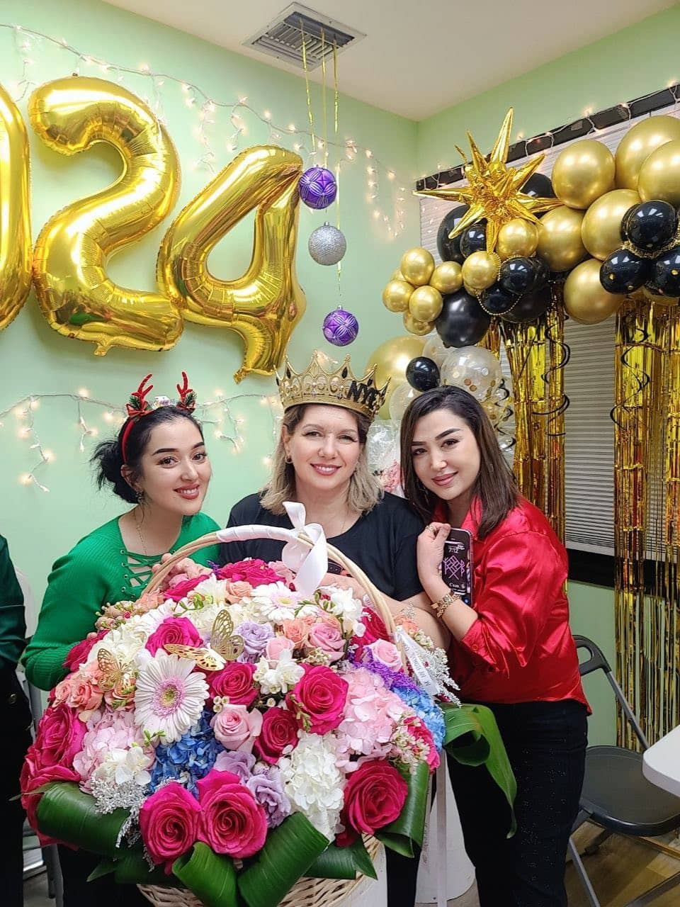 Three students with a large flower basket under 2024 balloons at a New Year celebration